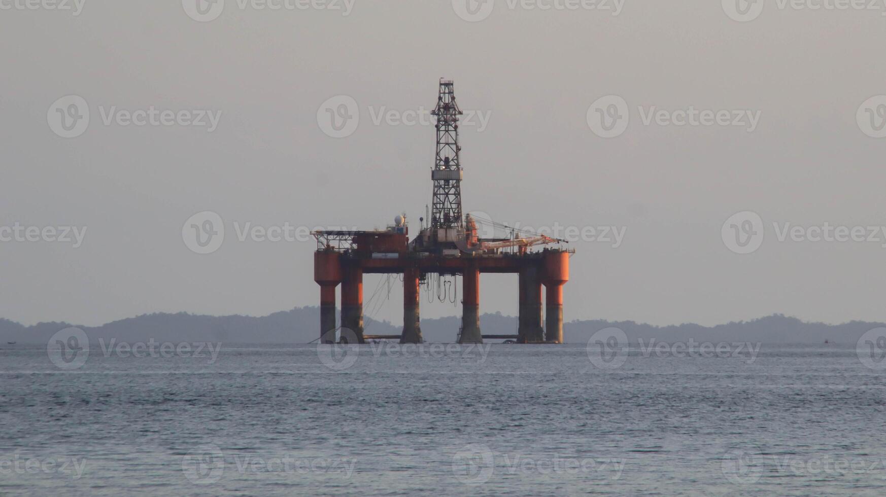 Offshore oil platform drilling site or oil rig project seen far in the middle of the sea. photo