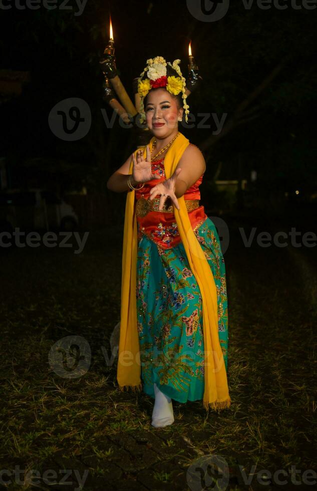 a traditional Javanese dancer dances with colorful flowers on her fist while on stage photo