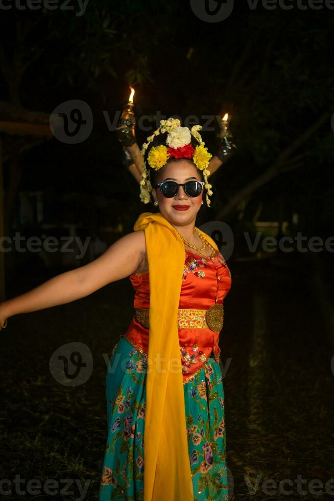 a traditional Javanese dancer stands and dances with a flexible body while wearing sunglasses photo