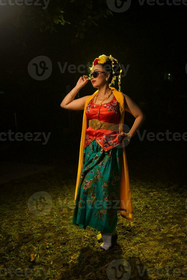portrait of a traditional Javanese dancer dancing with very beautiful hand movements while wearing sunglasses photo
