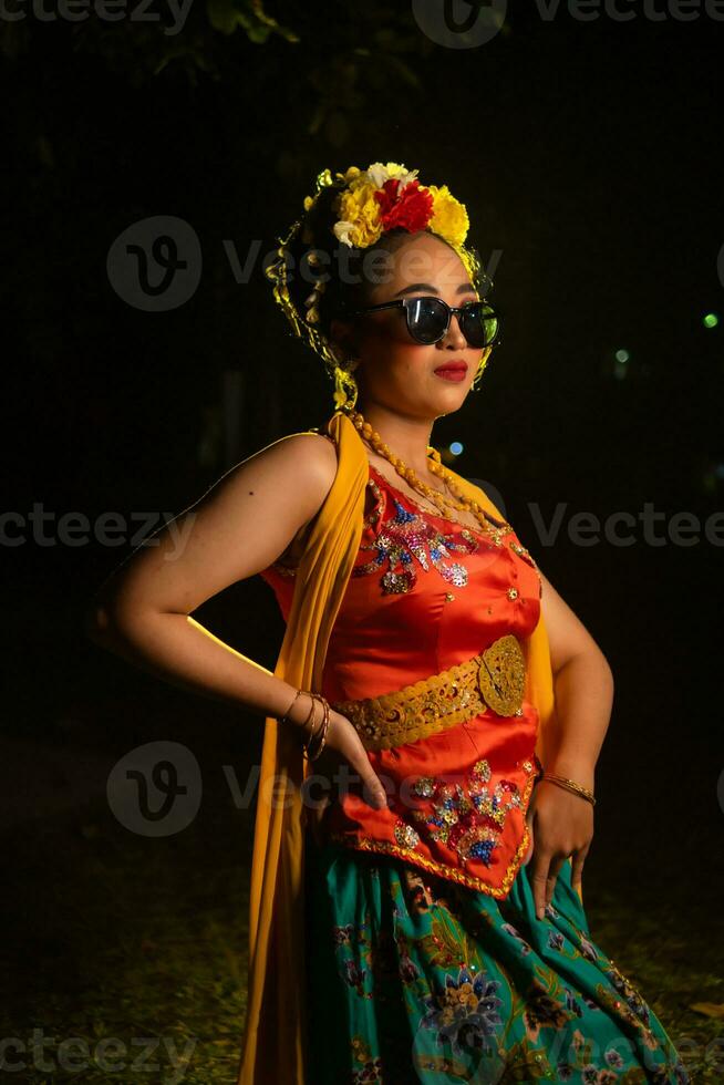 un tradicional javanés bailarín soportes y bailes con un flexible cuerpo mientras vistiendo Gafas de sol foto