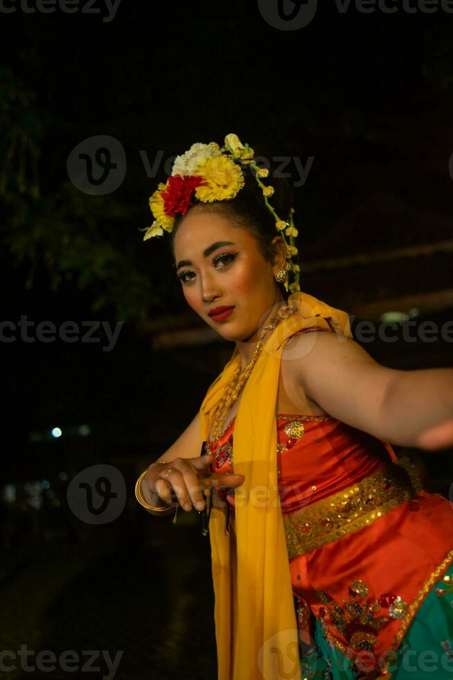 portrait of a traditional Sundanese dancer dancing with an orange scarf hanging down her body photo