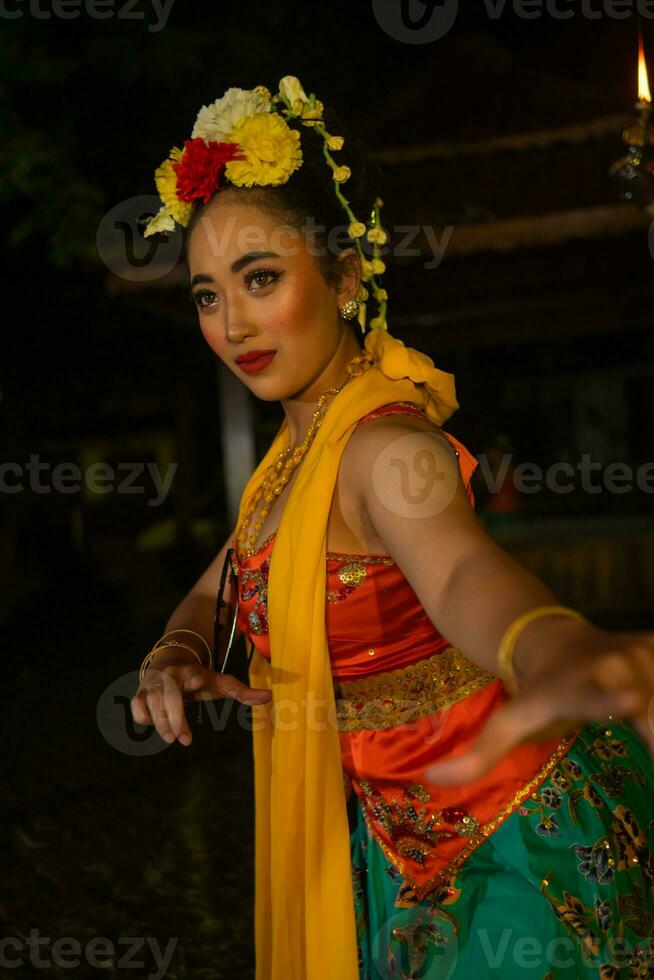 portrait of a traditional Sundanese dancer dancing with an orange scarf hanging down her body photo