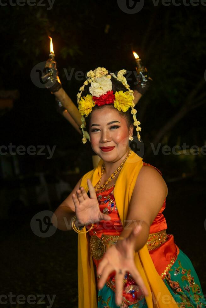 a traditional Javanese dancer dances with colorful flowers on her fist while on stage photo