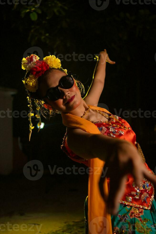 a Sundanese dancer dances very agilely while wearing sunglasses on her face photo