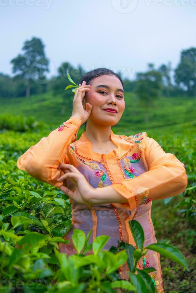 a Javanese woman on vacation in a tea garden wearing a yellow dress photo