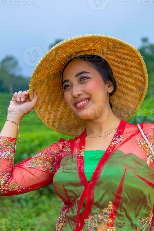 un té hoja granjero participación un bambú sombrero mientras trabajando en el té jardín foto