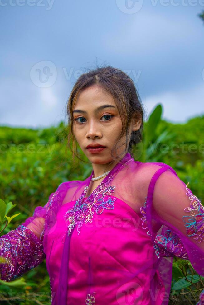 an Asian woman posing very sexy among the tea plantations while wearing a pink dress photo