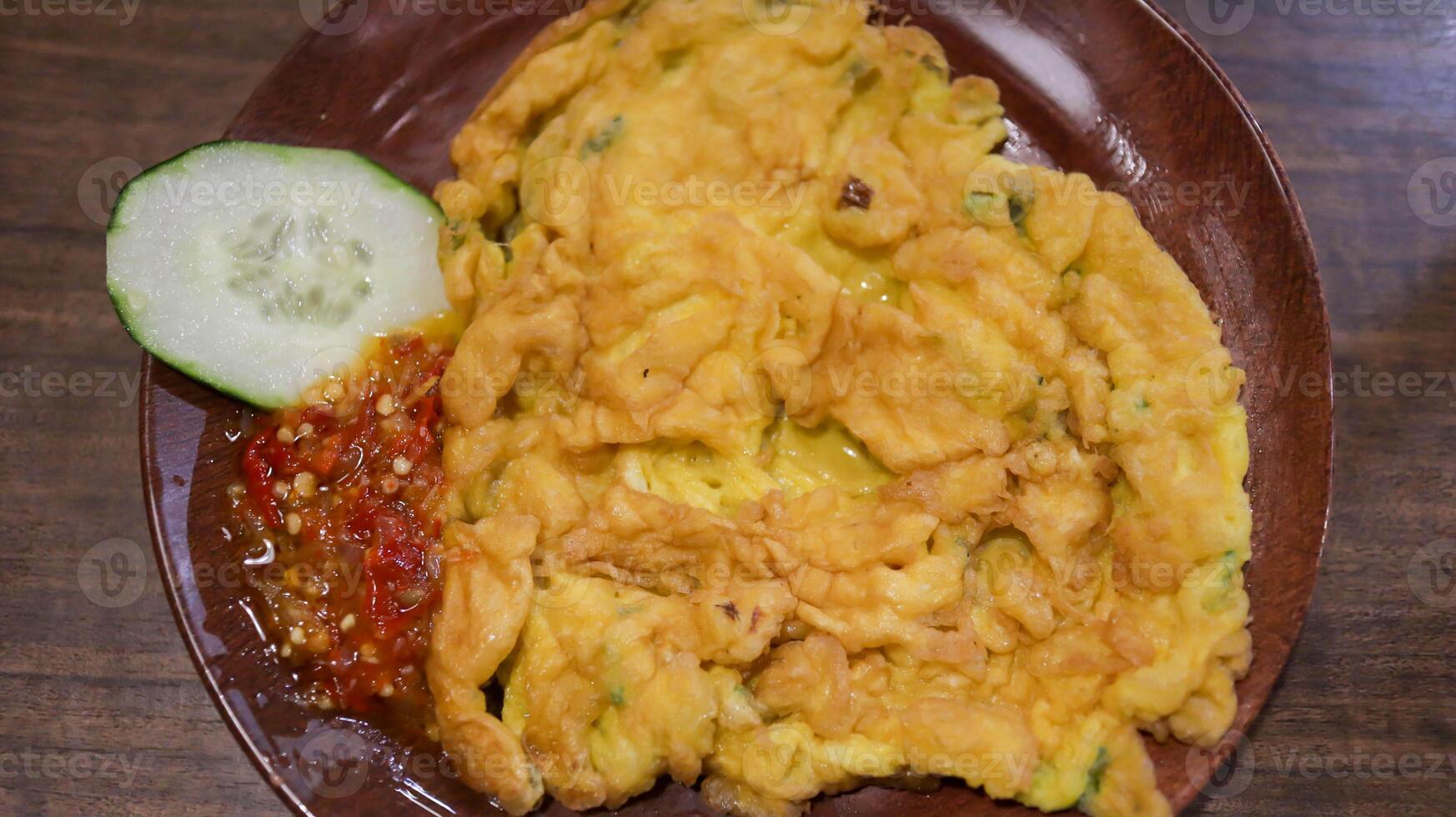 A plate of omelette egg with deep fried cook and traditional sambal or mashed chili sauce. Indonesian style cuisine. photo