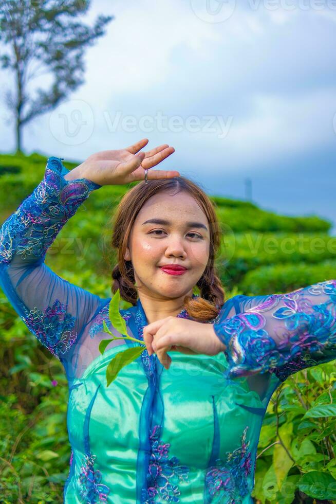 a beautiful Asian teenager is posing in a tea garden in her blue dress photo