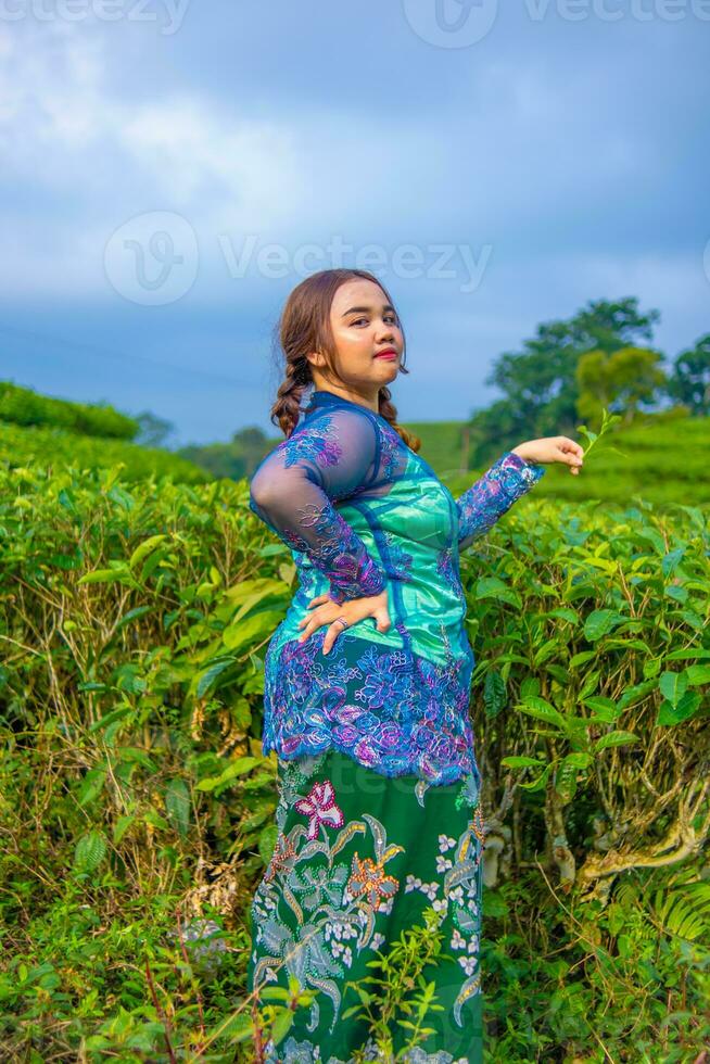 a beautiful Asian woman is posing in her blue dress in front of a park photo