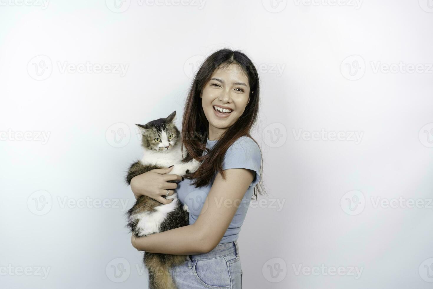 Portrait of young Asian woman holding cute angora cat with yellow eyes. Female hugging her cute long hair kitty isolated by white background. Adorable domestic pet concept. photo