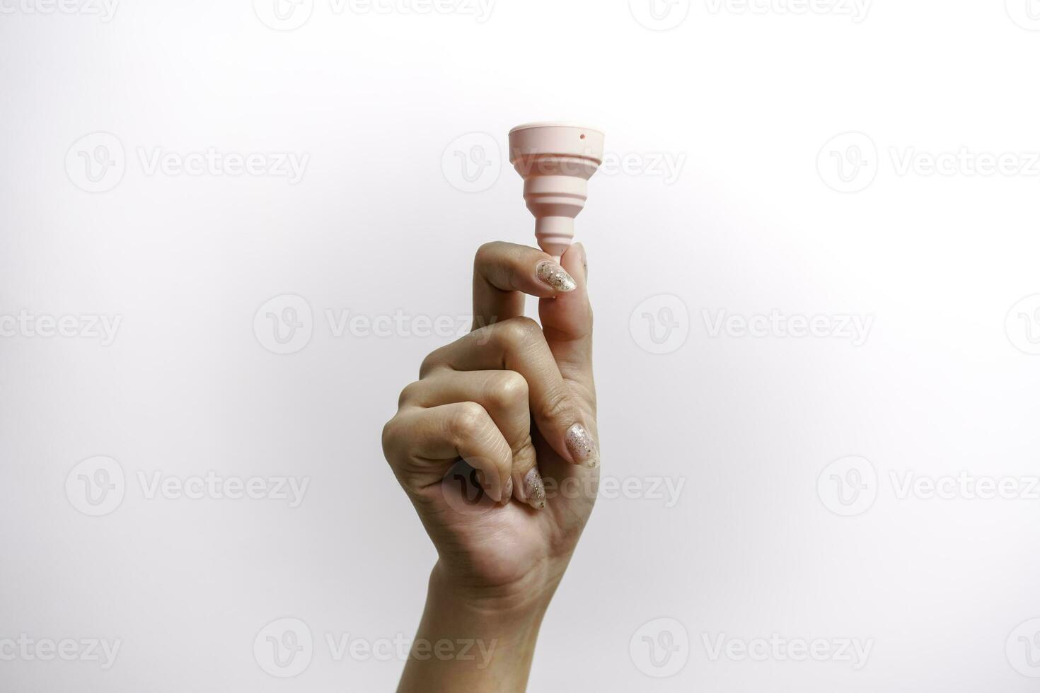 Close up of woman hand holding menstrual cup over white background. Women health concept, zero waste alternatives photo