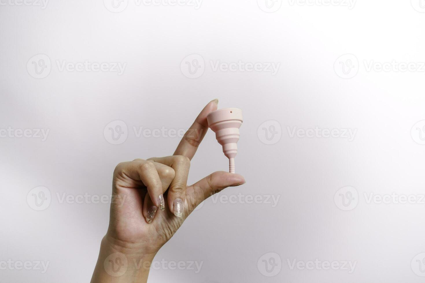 Close up of woman hand holding menstrual cup over white background. Women health concept, zero waste alternatives photo