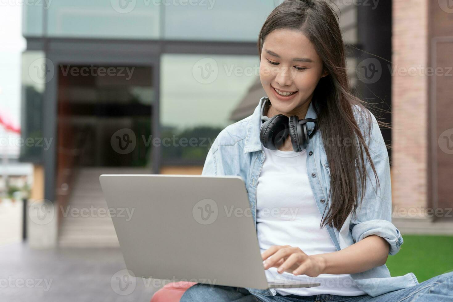 Beautiful Asian woman female student excited checking language test results on laptop. Smile girl happy study online. book in college campus. Portrait female on international Asia University photo