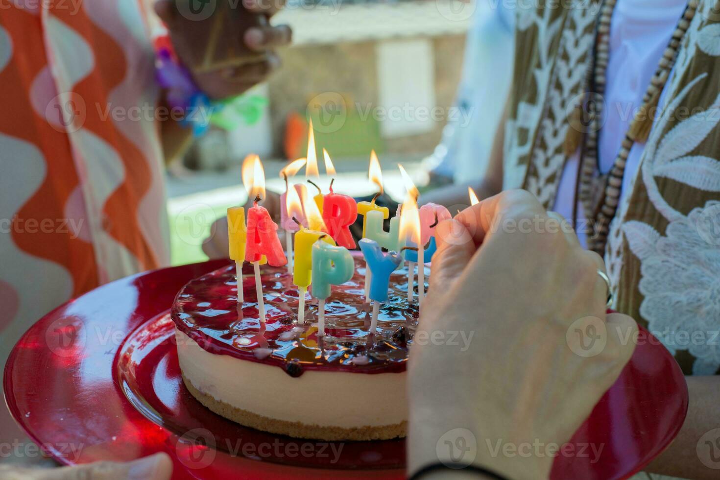 Caucasian hands lighting candles on a birthday cake. photo