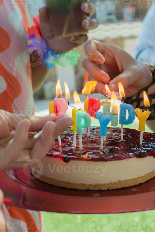 Caucasian hands lighting candles on a birthday cake. photo