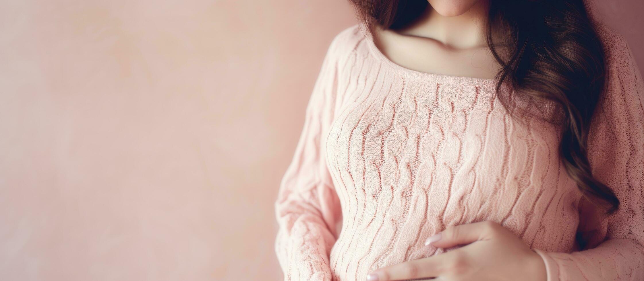 Pregnant woman with round belly wearing pink sweater photo