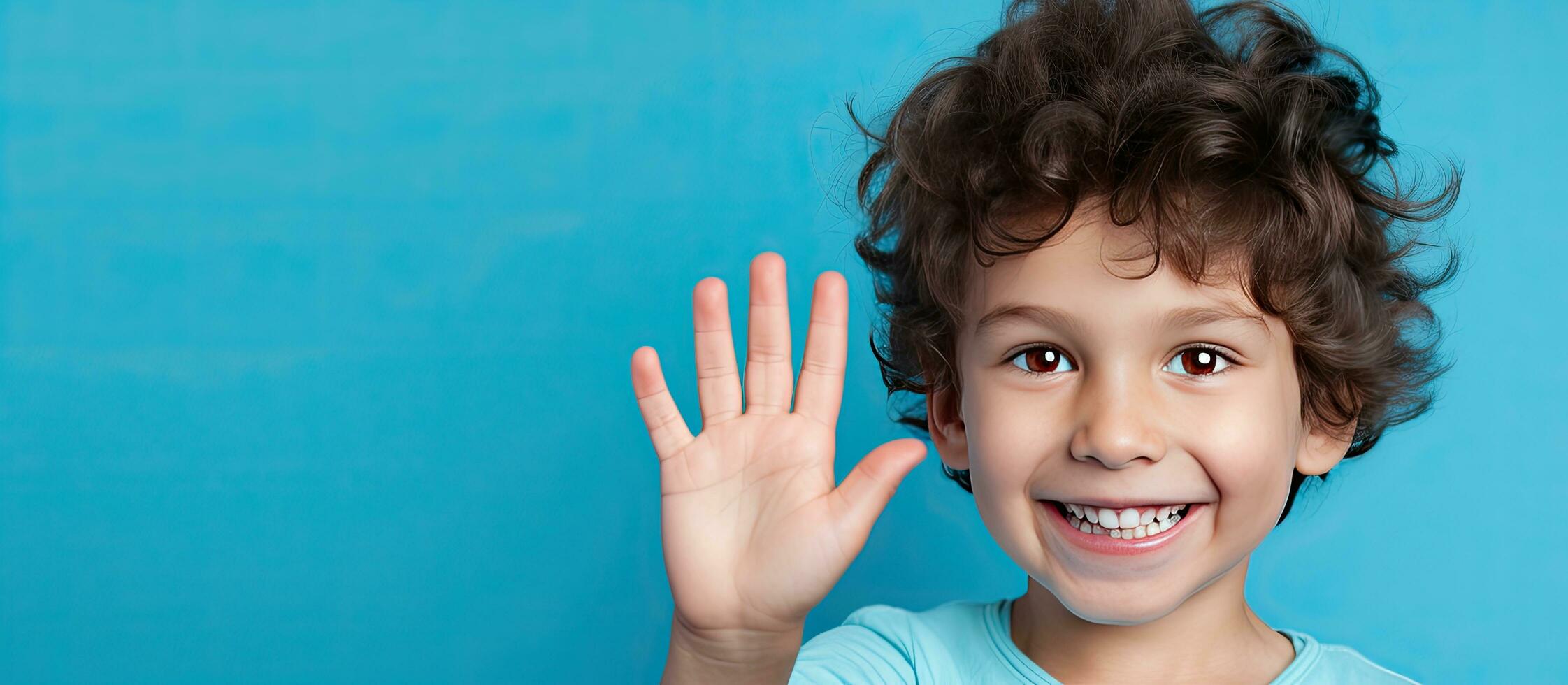 Portrait of a five year old boy displaying five fingers on a blue background with empty space photo
