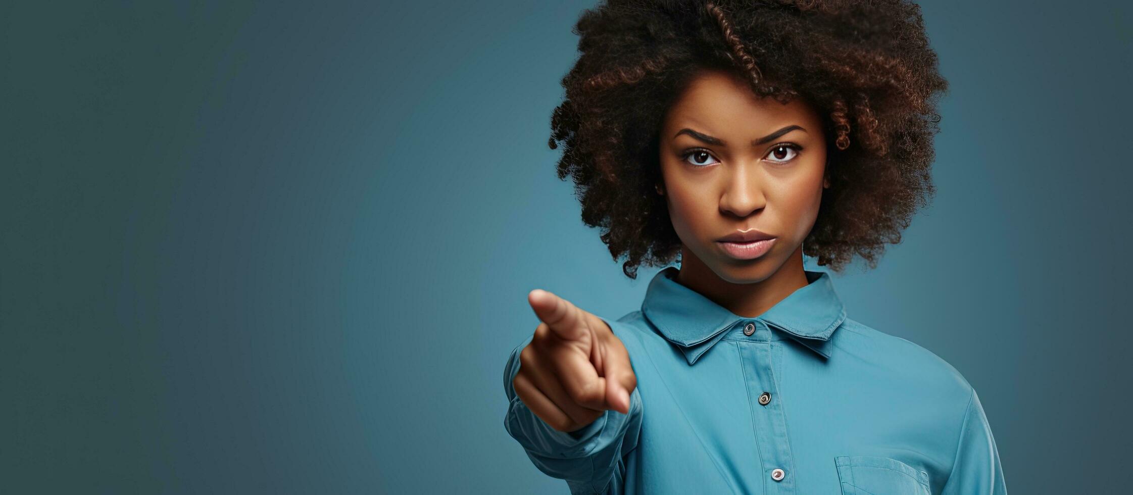 A calm African American woman in casual attire pointing to an advertisement with a serious expression photo