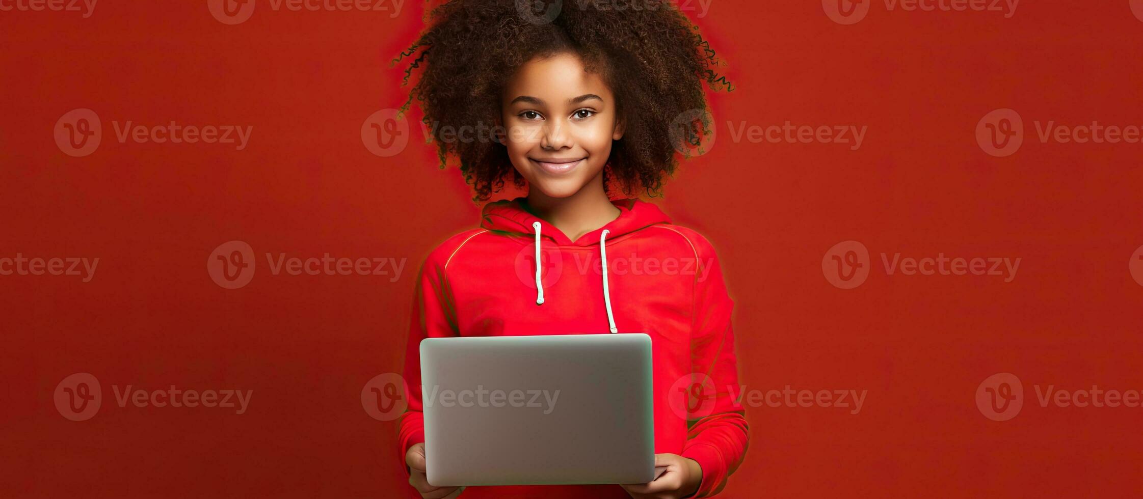 Smiling young African American girl with laptop on red wall background studio portrait People lifestyle concept Mock up copy space photo