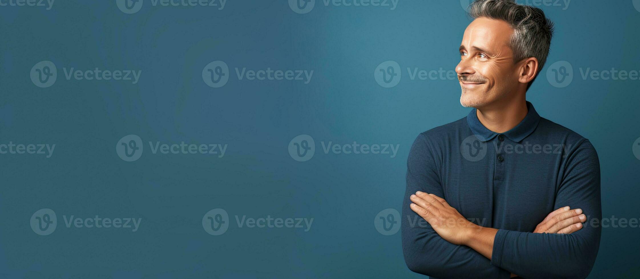 A mature and confident man feeling joyful and optimistic gazes up with arms crossed photo