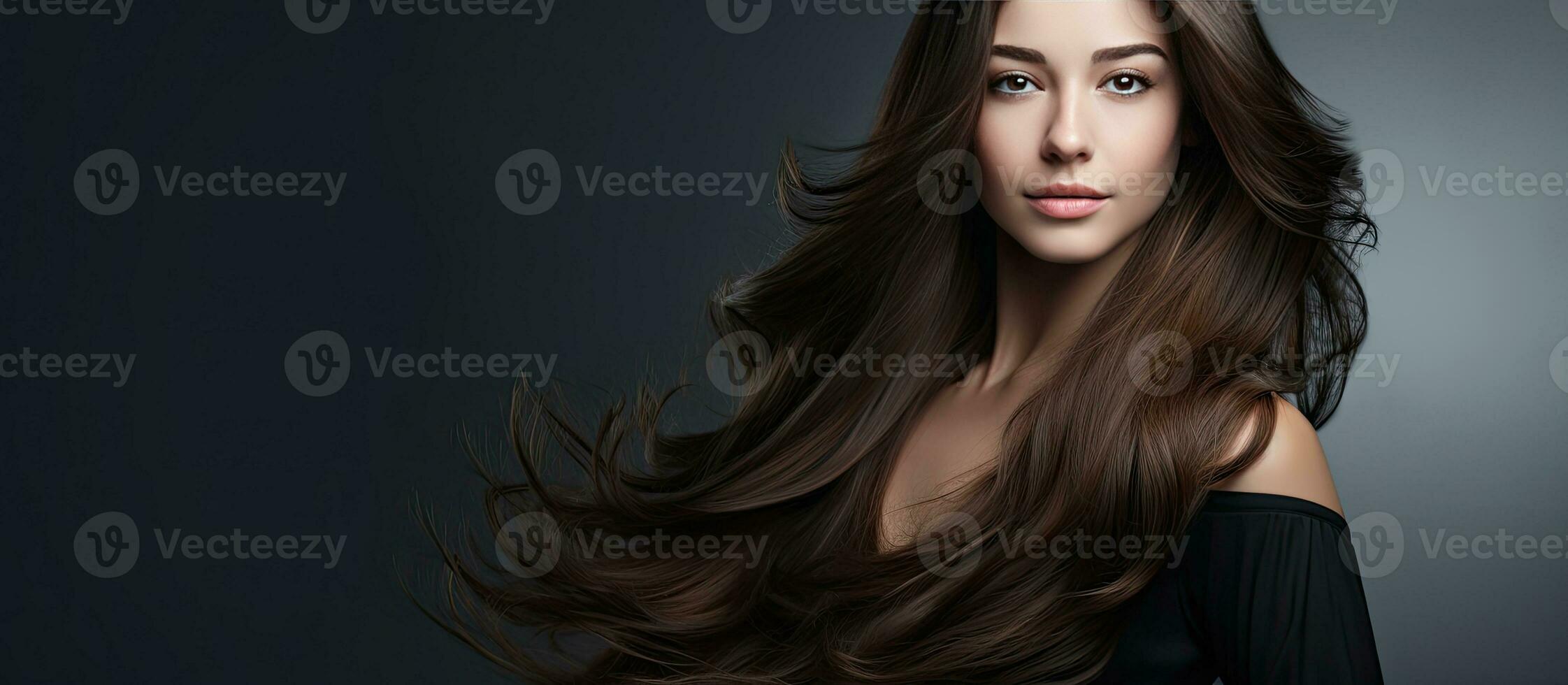 Young stylish female with long thick hair posing against gray studio background left space for advertising Haircare products concept photo