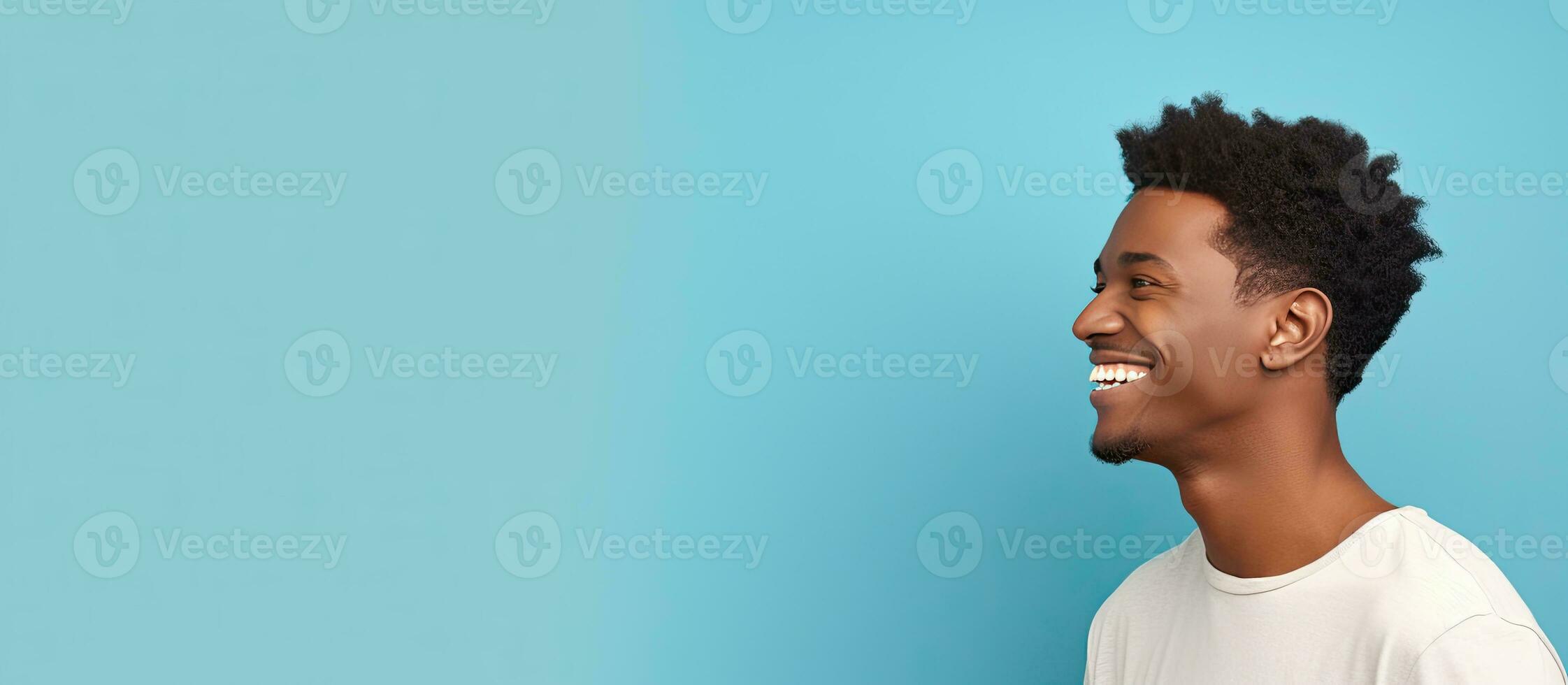 Side view of young African American man smiling and looking aside isolated on blue background with copy space photo