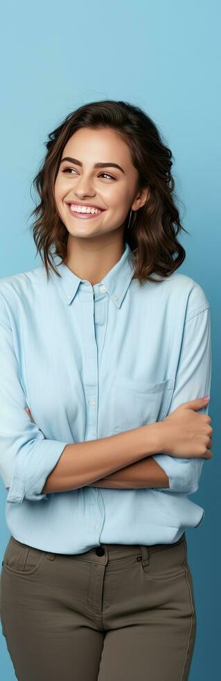 Casually dressed woman on blue background smiling and presenting blank copy space photo