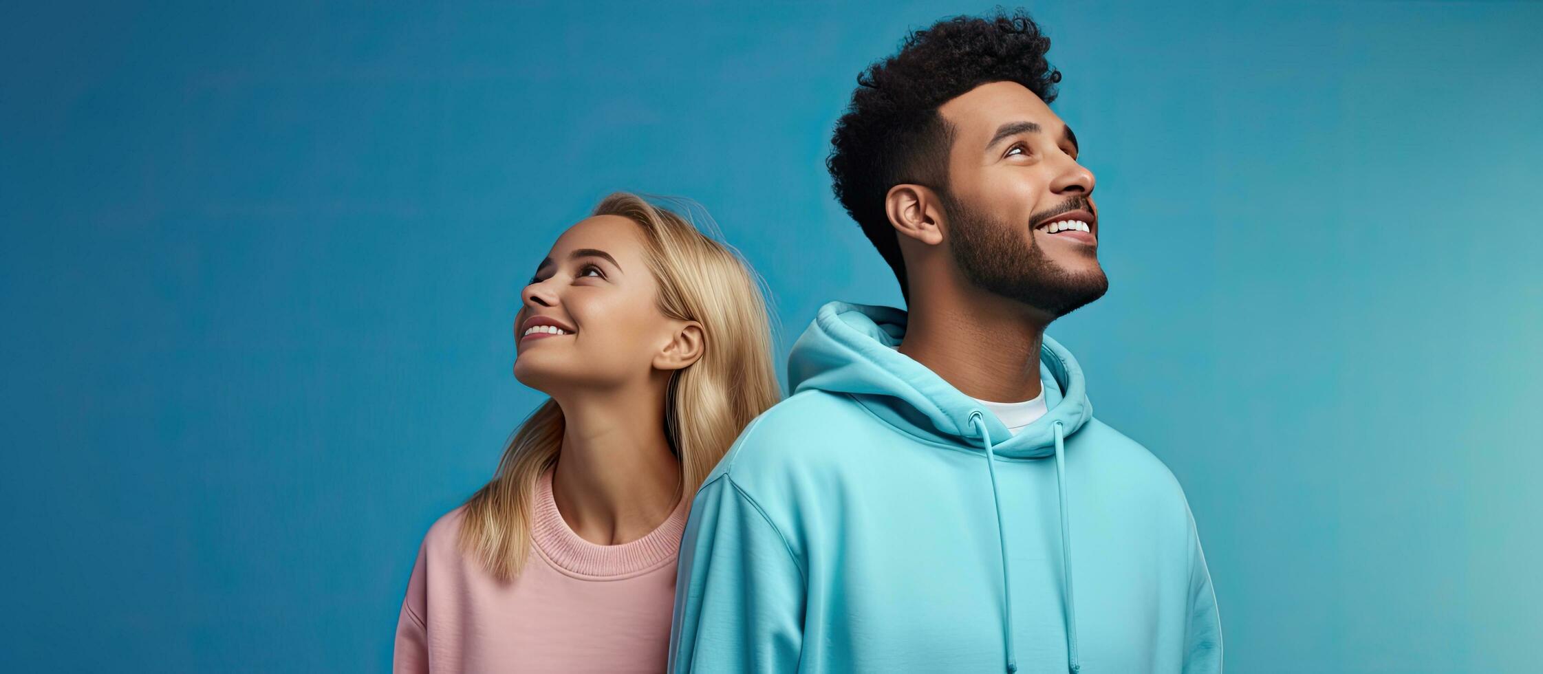 Cheerful young couple in hoodies standing isolated looking away at copy space photo