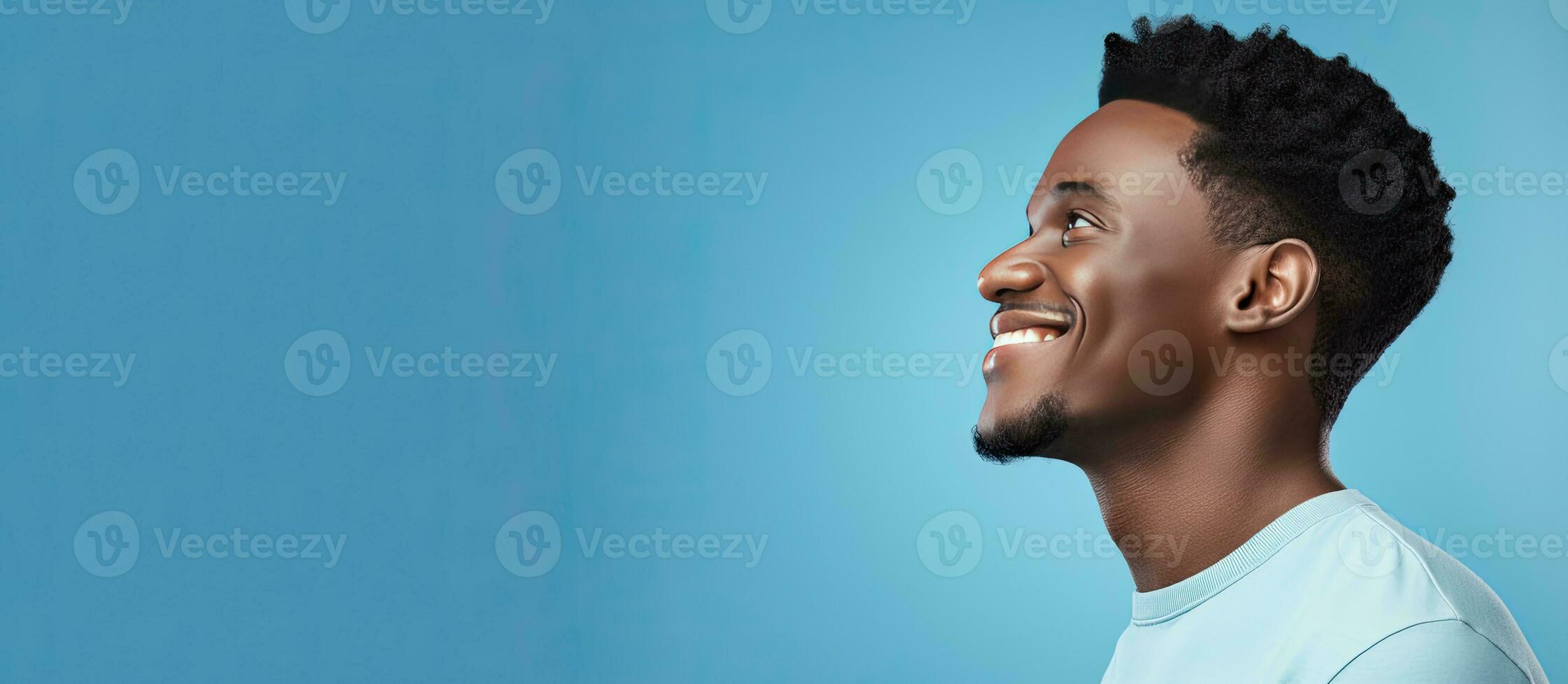 Side view of young African American man smiling and looking aside isolated on blue background with copy space photo