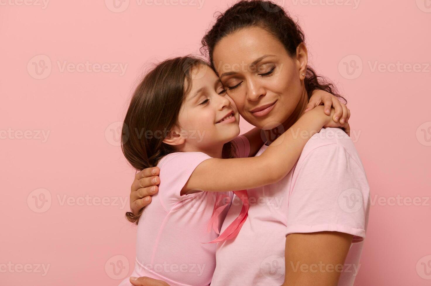 Beautiful loving mother and daughter, hugging each other, wearing pink clothes with pink ribbon, symbol of World Breast Cancer awareness Day in October. World Cancer Day, national Cancer Survivor Day. photo