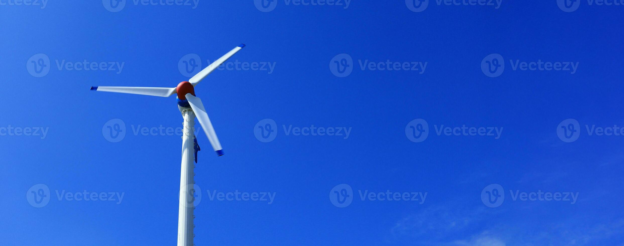 The wind turbine generates an environmentally friendly electricity in the bright blue sky. photo