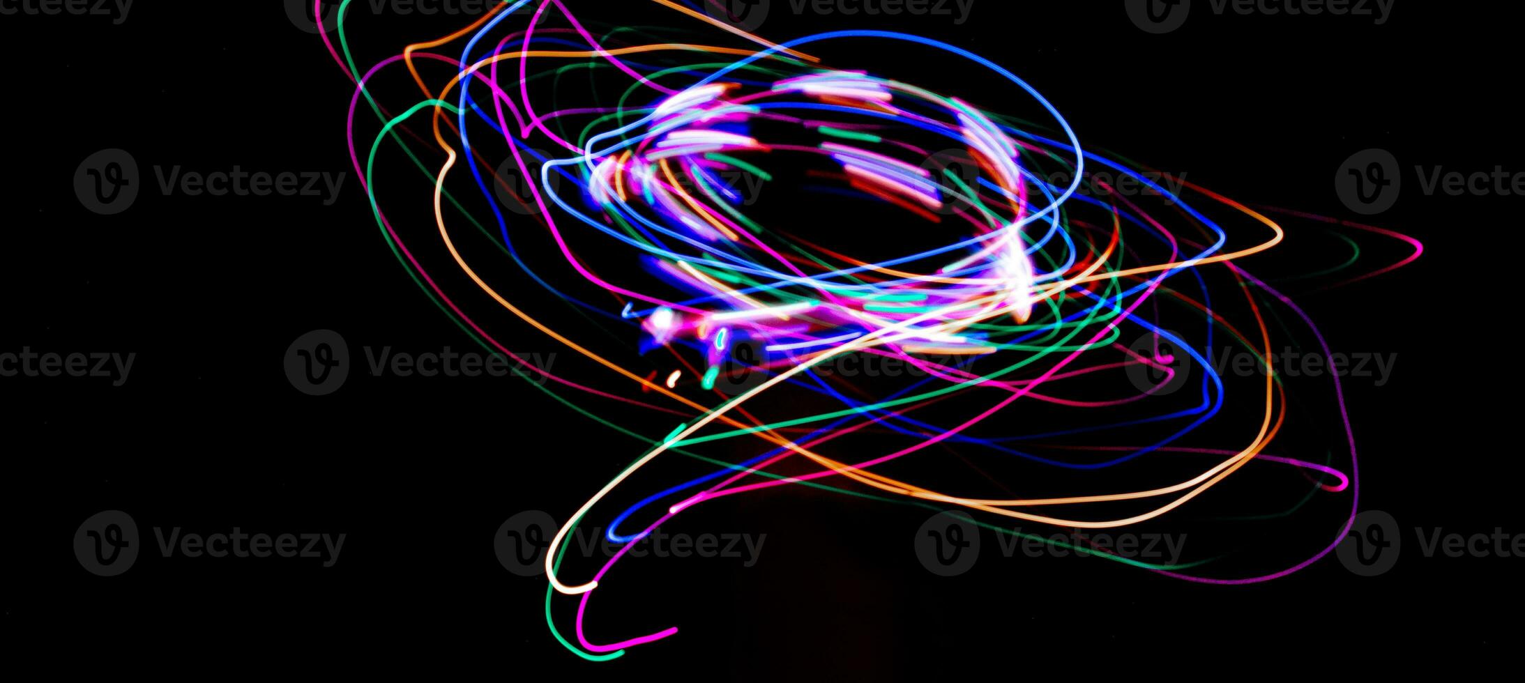 Multi color light painting photography, swirl and curve of blue, green and red light against a black background. photo