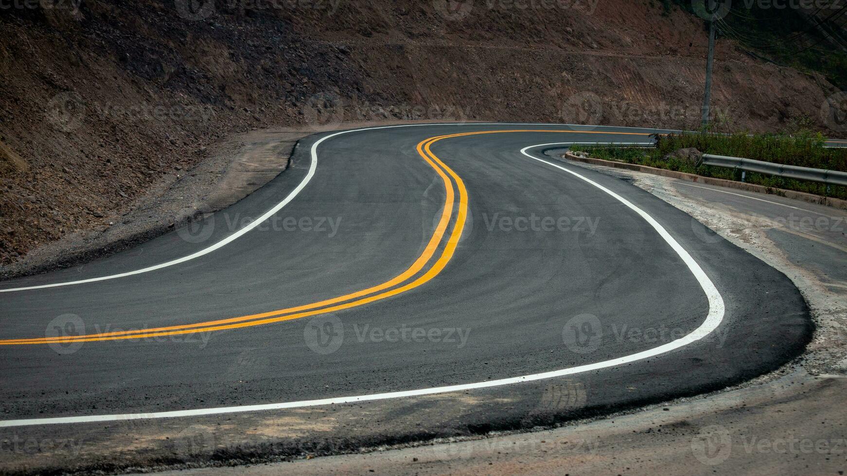 el asfalto la carretera tiene amarillo y blanco tráfico líneas cruce el montañas. foto