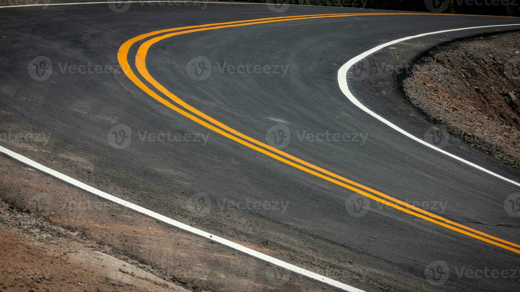 The asphalt road has yellow and white traffic lines crossing the mountains. photo