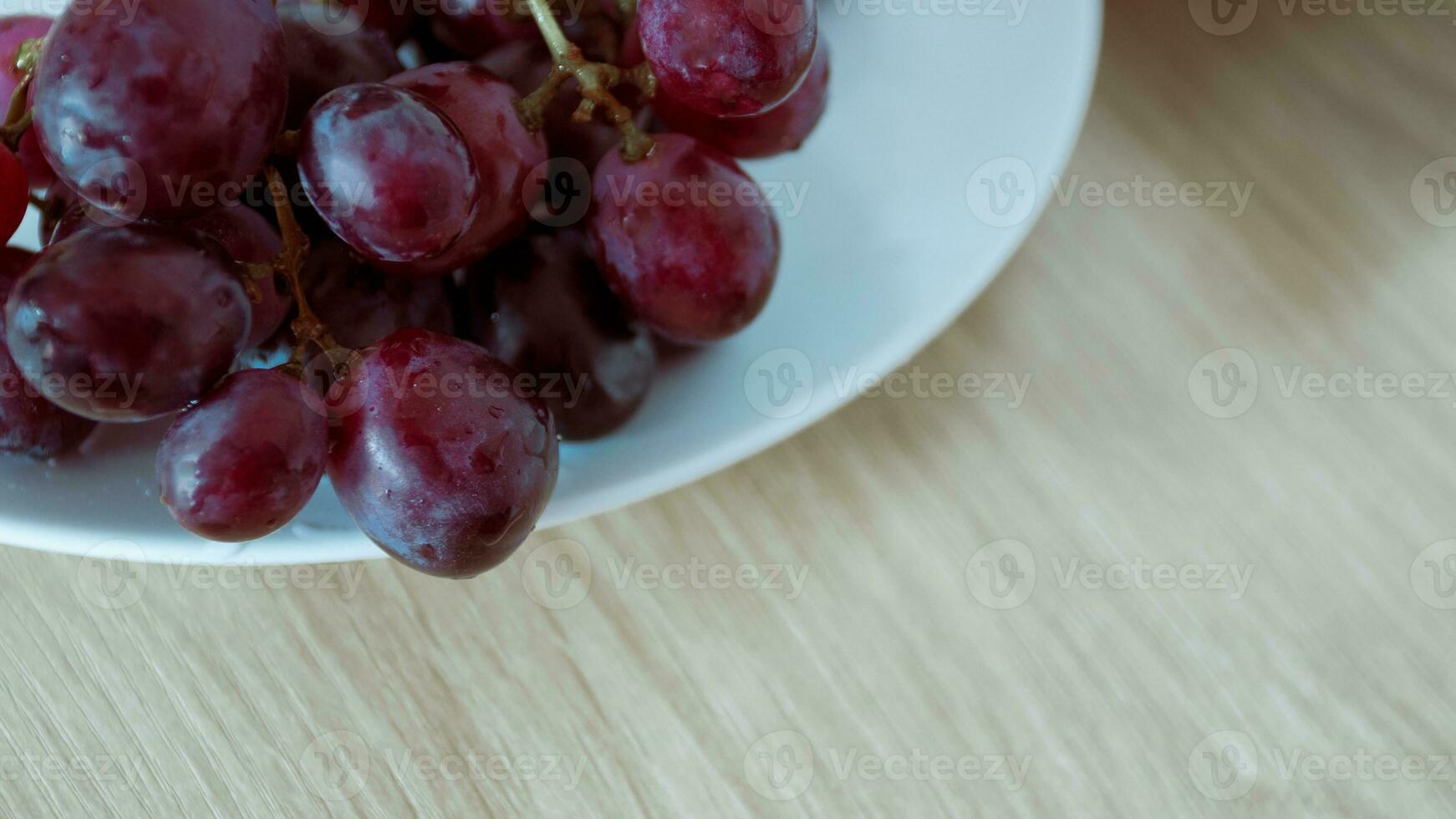 Close-up of grapes with water droplets on a white ceramic plate. photo