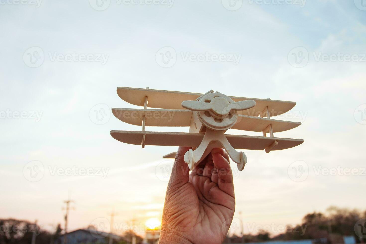 Freedom concept, human hand holding wooden plane on the sunset sky background photo