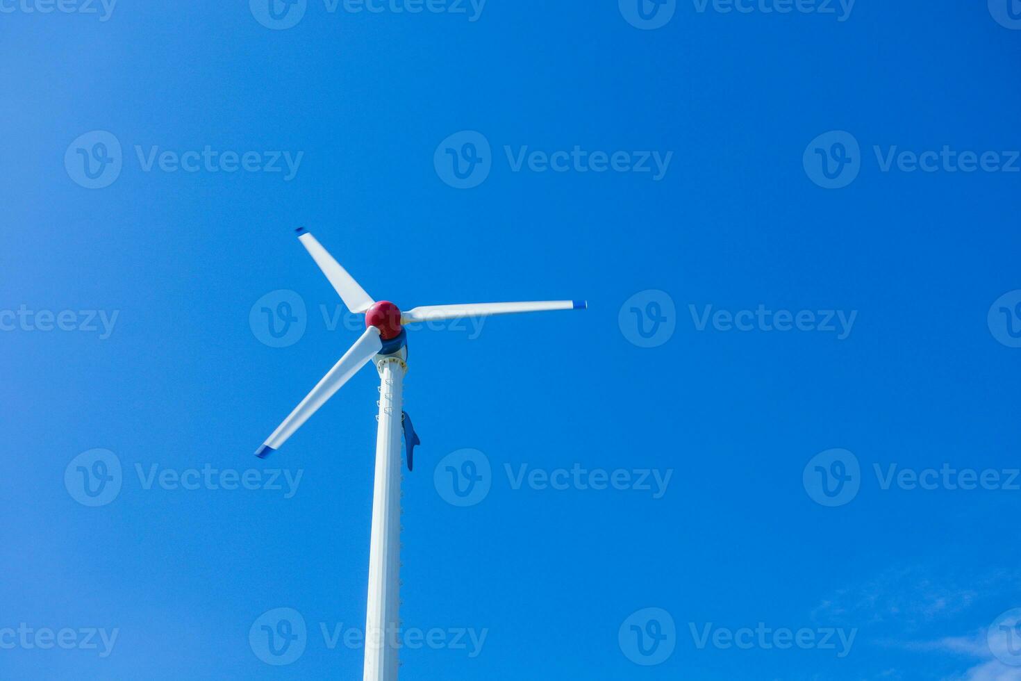 The wind turbine generates an environmentally friendly electricity in the bright blue sky. photo