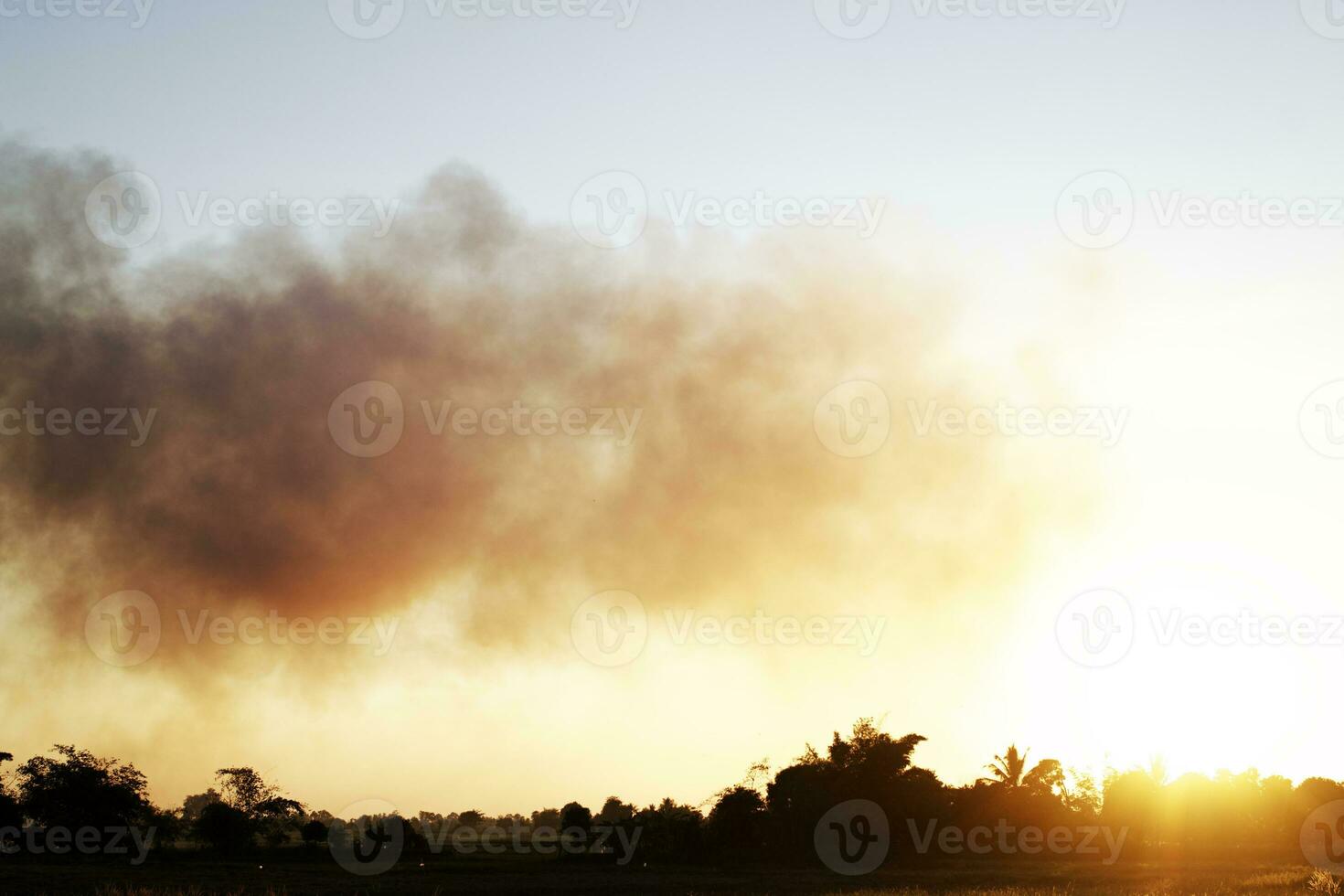 Many black smoke rise in the sky at sunset. The concept of weather is pollution. photo