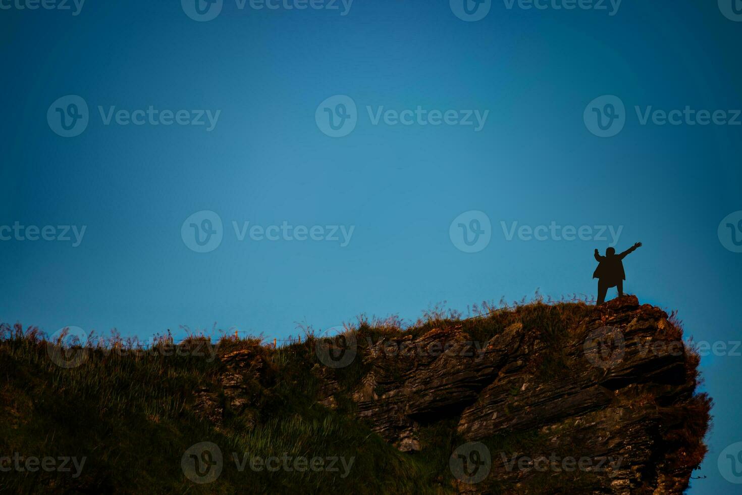 silhouette of man on mountain top over sky and sun light background,business, success, leadership, achievement and people concept photo