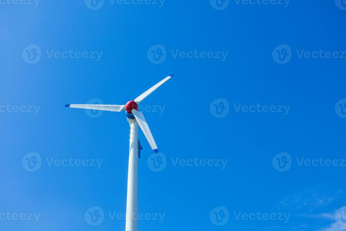The wind turbine generates an environmentally friendly electricity in the bright blue sky. photo