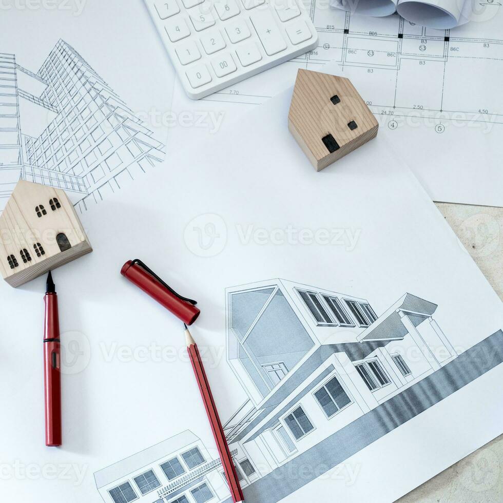 Paper rolls, construction drawings, calculators and wooden house models on concrete floors. photo