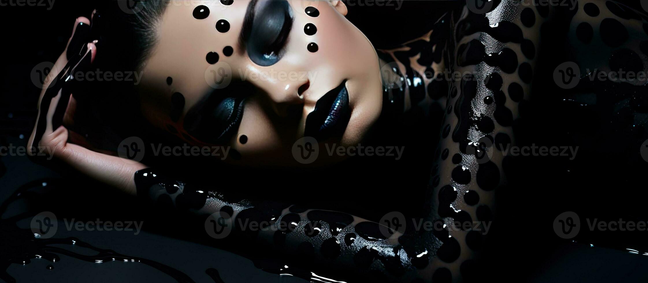 Abstract body painting art featuring a young woman with black hair lying on a shiny black floor with creative black dot accents photo