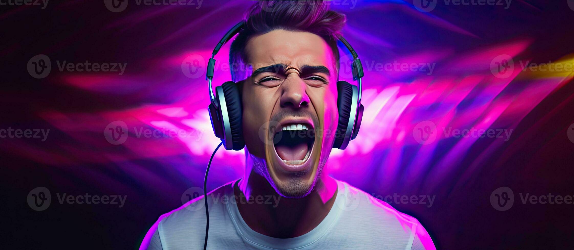 Male vocalist wearing headphones listening to music singing with open mouth recording studio DJ hipster lifestyle portrait with purple background neon lig photo