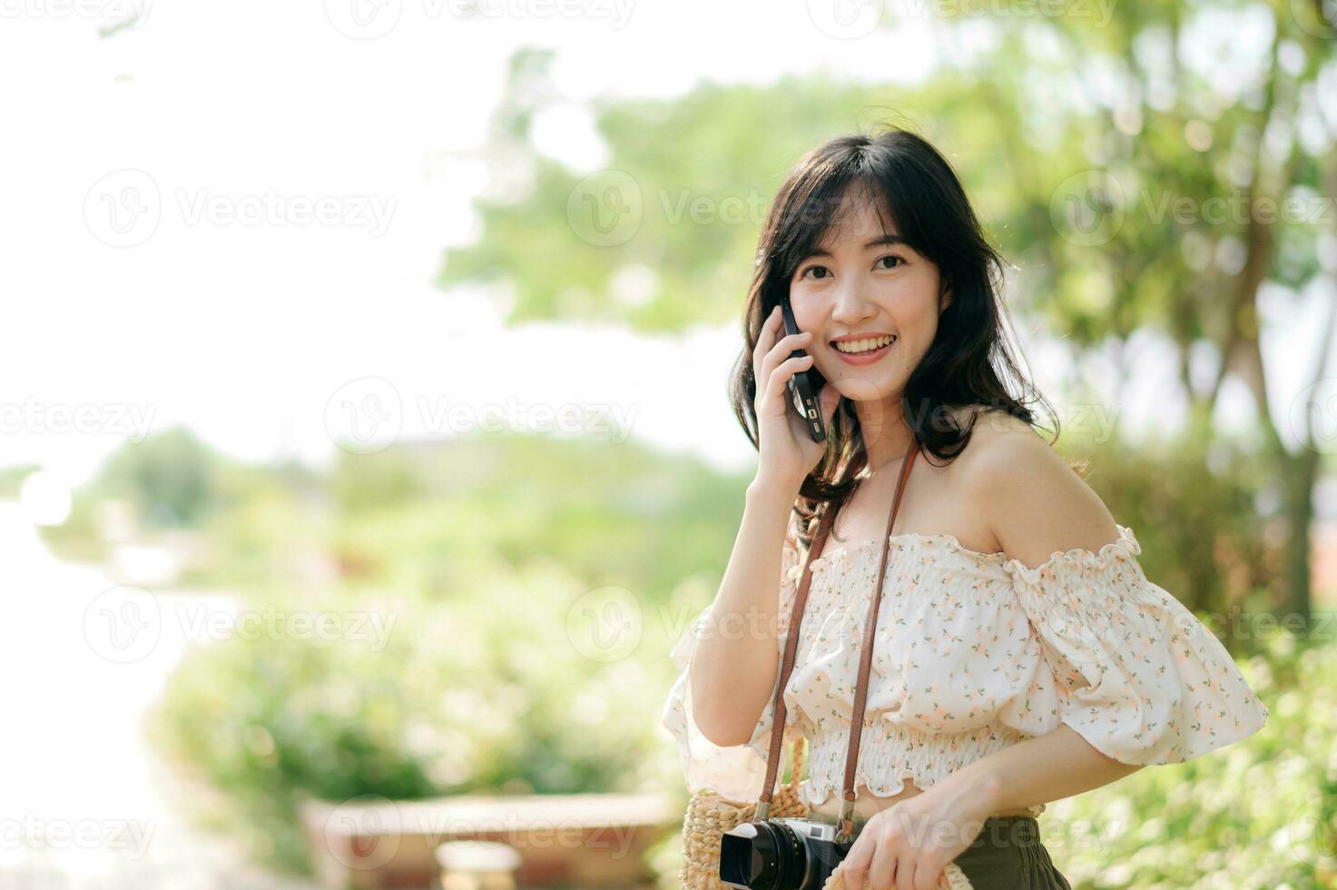 Portrait of asian young woman traveler with weaving hat, basket, mobile phone and camera on green public park background. Journey trip lifestyle, world travel explorer or Asia summer tourism concept. photo