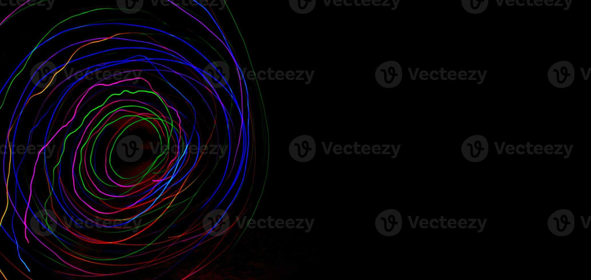 Multi color light painting photography, swirl and curve of blue, green and red light against a black background. photo