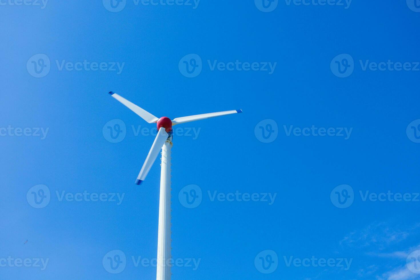 The wind turbine generates an environmentally friendly electricity in the bright blue sky. photo