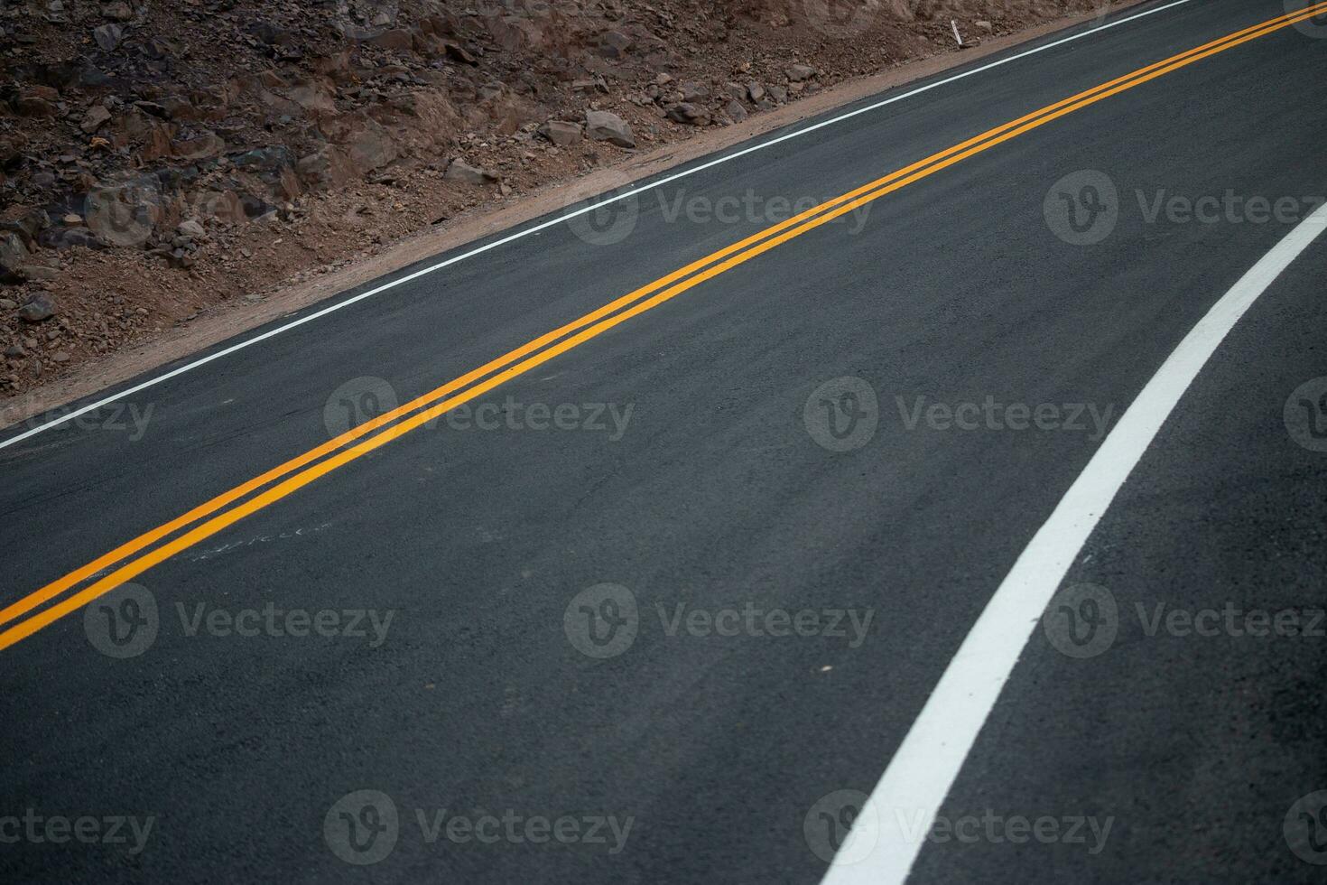 The asphalt road has yellow and white traffic lines crossing the mountains. photo