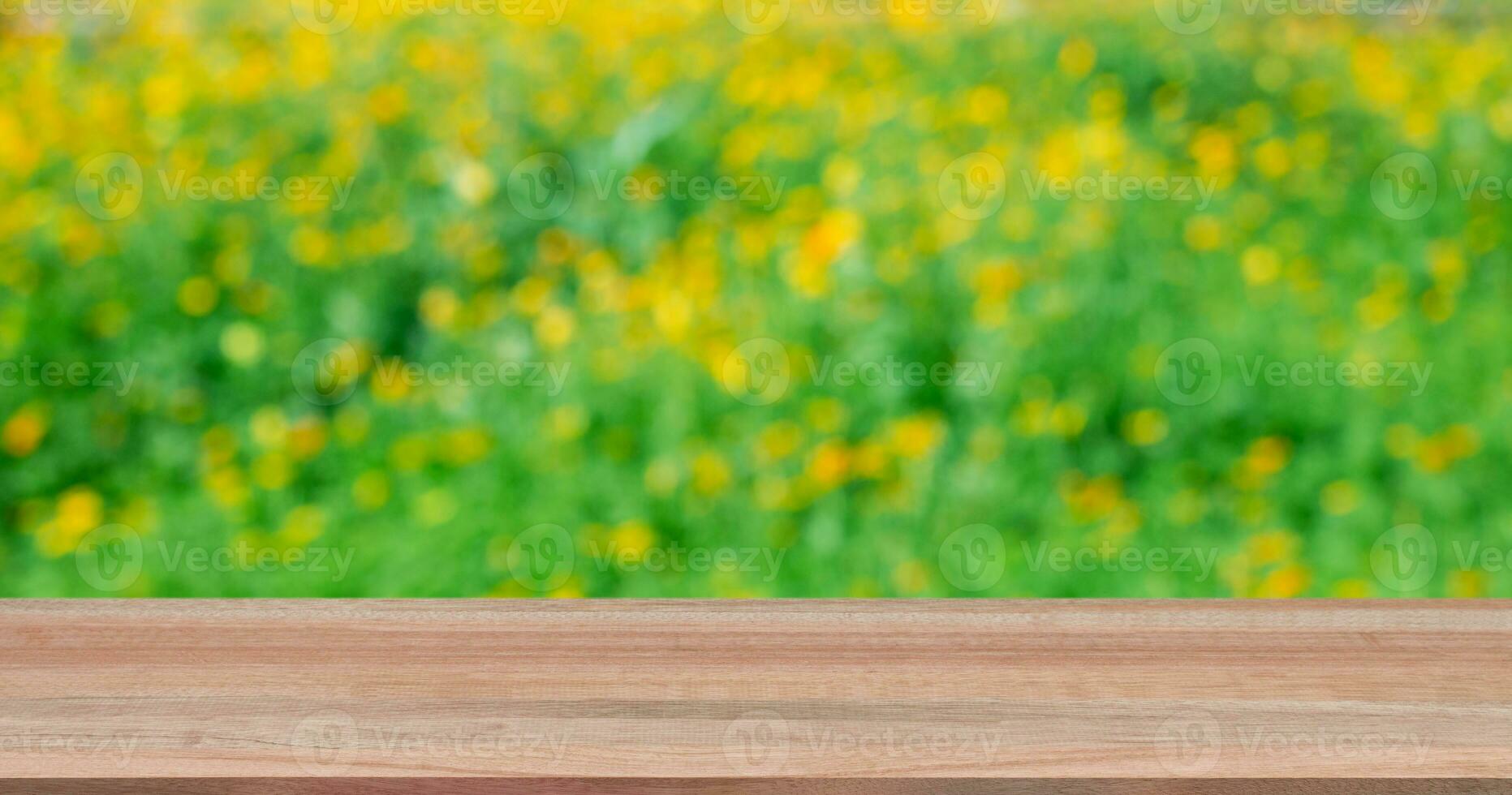 Wooden table with flowers field blurred background. photo